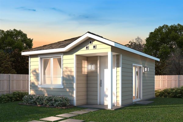 A detached ADU a creme colored detached ADU on a lot surrounded by a wooden fence with trees in the background