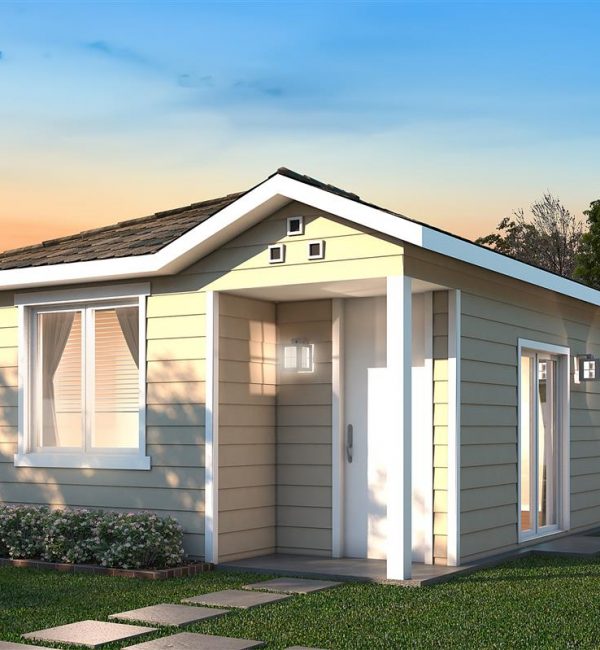 A detached ADU a creme colored detached ADU on a lot surrounded by a wooden fence with trees in the background